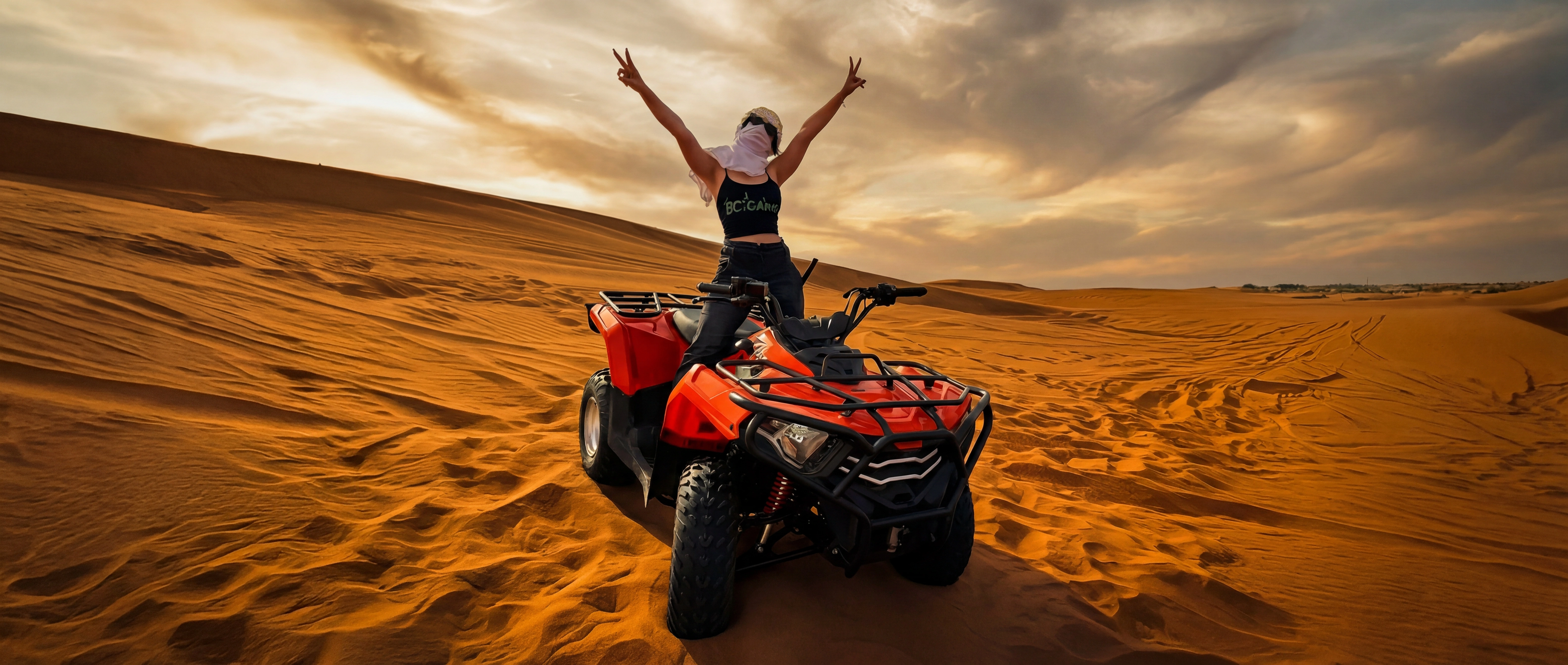 Jana on a quad bike in the Dubai desert β arms up, pure freedom energy